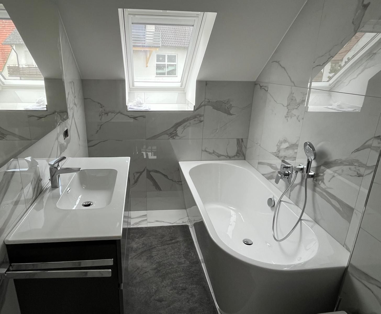 Fertiges Dachgeschossbad mit Waschtisch, Badewanne und Dachfenstern