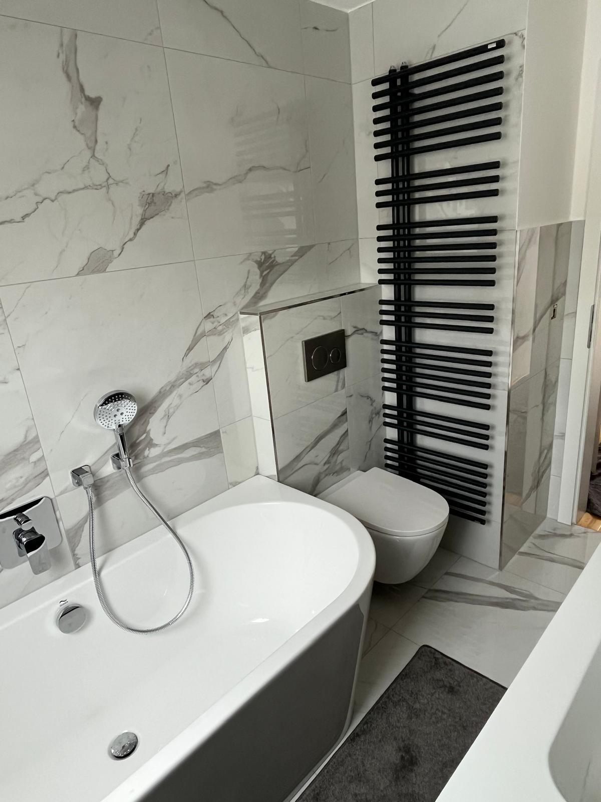 Badewanne mit Wandarmatur, WC und schwarzem Handtuchheizkörper