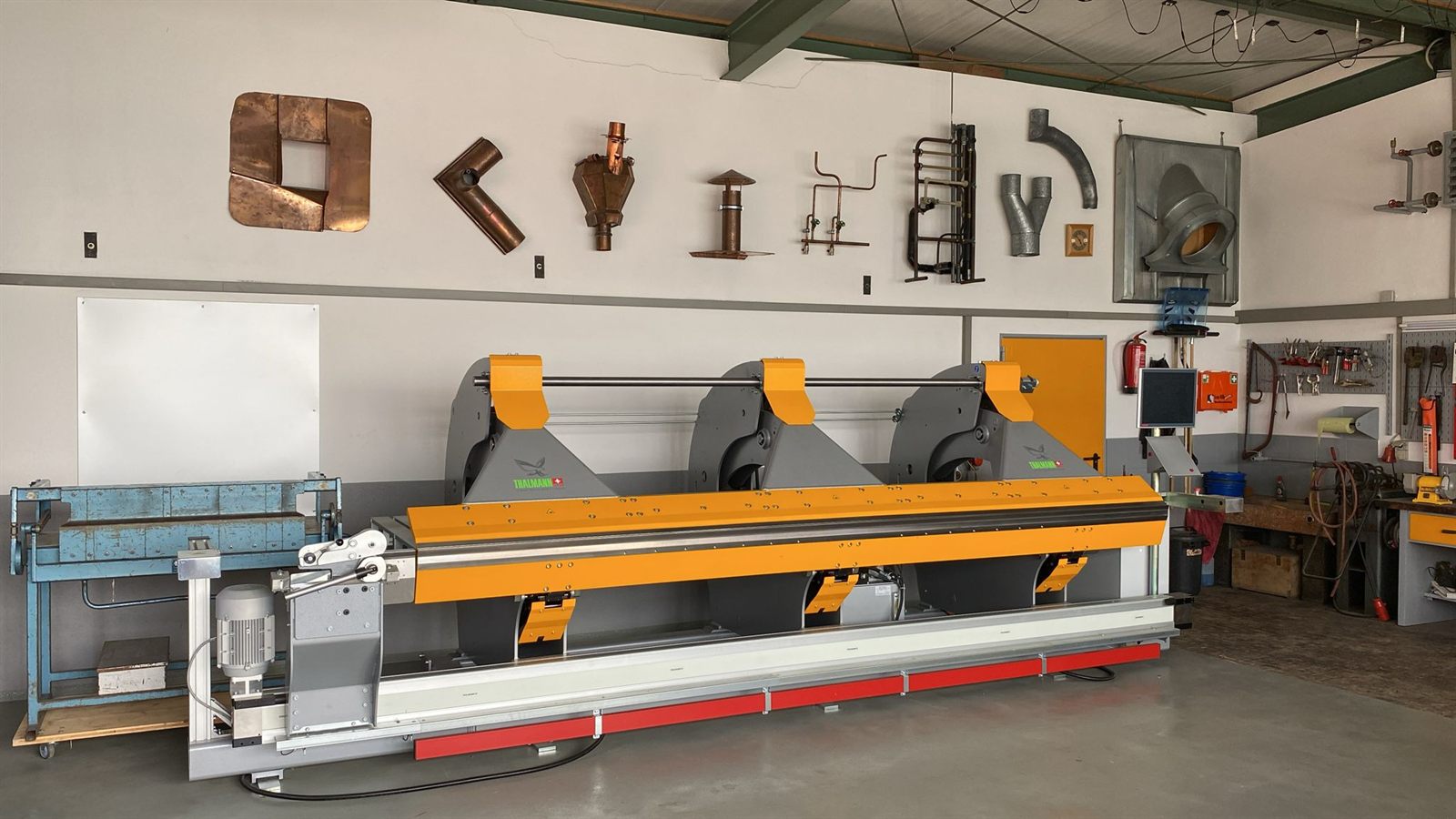Werkstatt mit Schwenkbiegemaschine und Blechstücken an der Wand